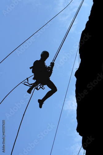 a man-climber rises on the wall with the help of the ropes