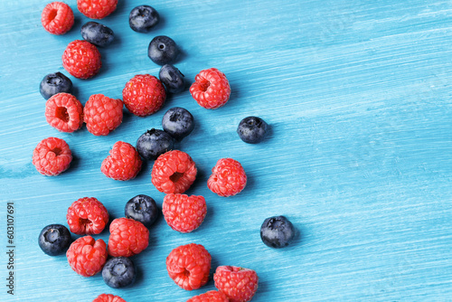 Raspberry and blueberry on blue background with copy space