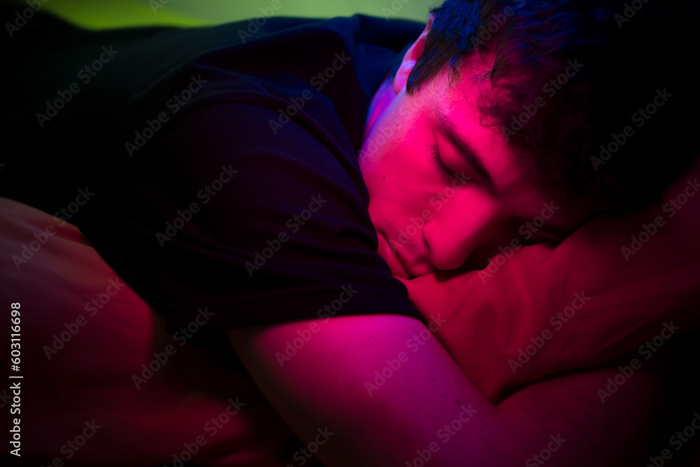 Young man sleeping on bed with neon lighting Young man sleeping on bed with neon lighting