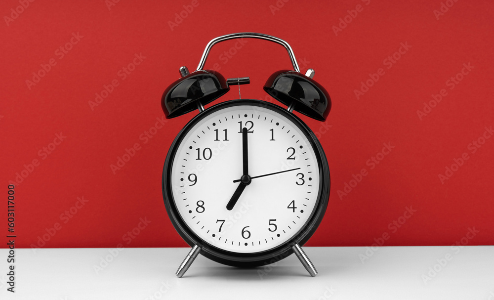 Black alarm clock on a red background Black alarm clock on a red background