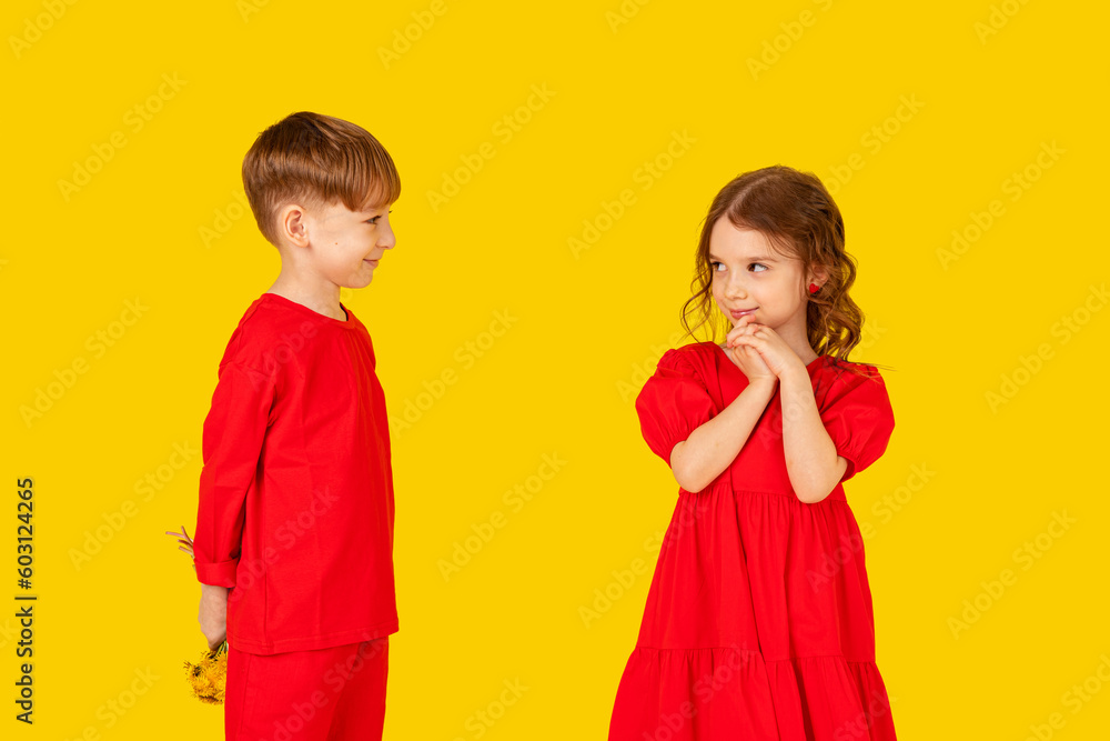 A little gentleman. Funny kids, happy little boy giving a cute girl bouquet of yellow spring flowers. Series in studio. Mother's Day, 8 March, the birthday, the International Women's Day A little gentleman. Funny kids, happy little boy giving a cute girl bouquet of yellow spring flowers. Series in studio. Mother's Day, 8 March, the birthday, the International Women's Day