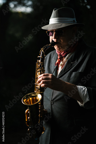 Adult man in hat playing saxophone on street photo