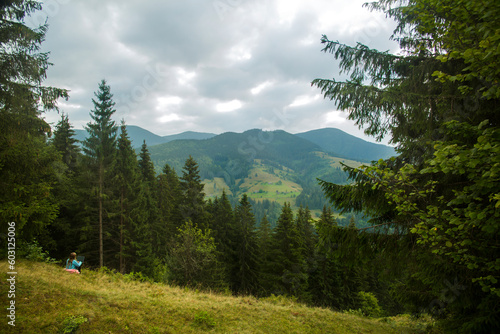 Young woman freelancer traveler working online using laptop and enjoying beautiful nature landscape with mountain