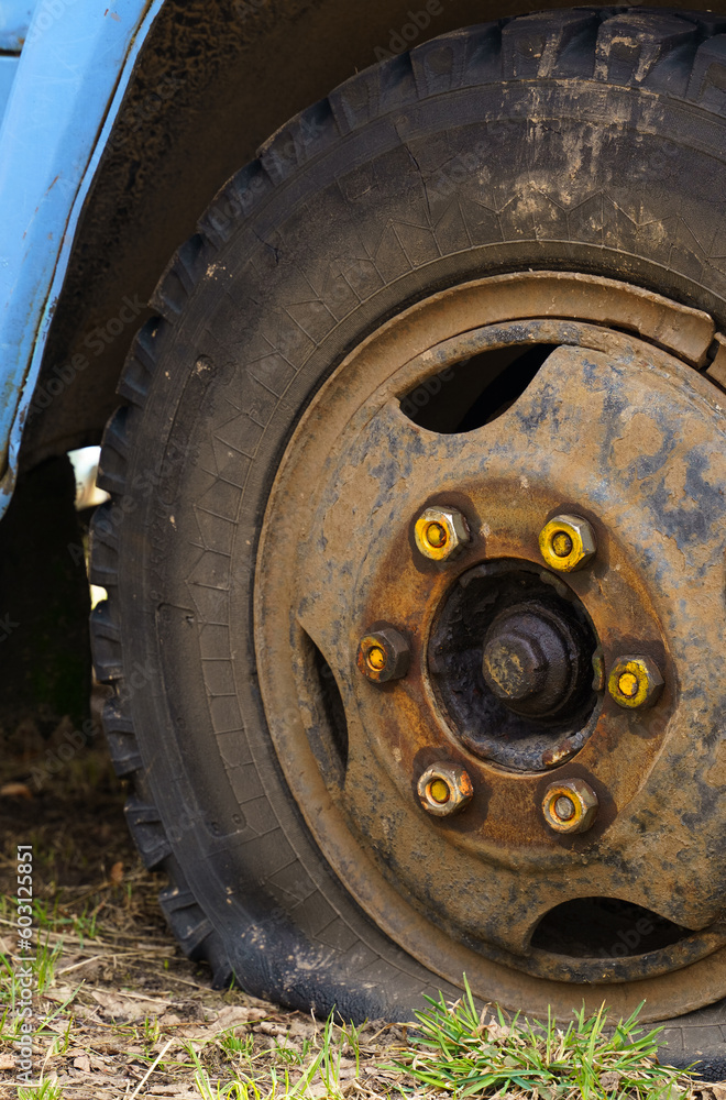 A flat tire of an old fragment of a rusty abandoned broken truck. A flat tire of an old fragment of a rusty abandoned broken truck.