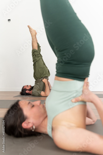 Calm couple performing Sarvangasana yoga pose photo