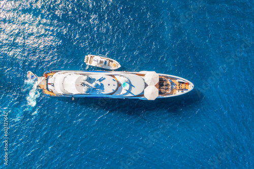 Aerial view of beautiful luxury yacht and boat in blue sea at sunset in summer. Sardinia island, Italy. Top view of speed boat, sea coast, transparent water. Travel. Tropical landscape. Yachting © den-belitsky
