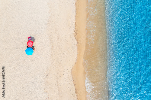 Aerial view of colorful umbrellas on empty sandy beach, blue sea at summer sunny day. Sardinia, Italy. Tropical background. Seascape. Turquoise water. Travel and vacation. Top drone view of ocean