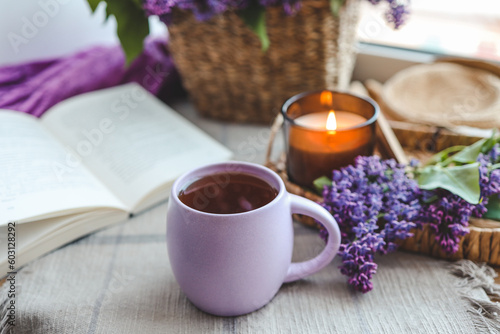 Cup of tea  straw hat  open book and lilac basket  spring still life