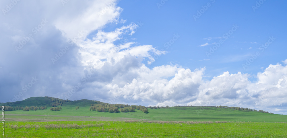 Beautiful hills covered with fresh greenery with shadows from cumulus clouds against a blue sky. Beautiful hills covered with fresh greenery with shadows from cumulus clouds against a blue sky.