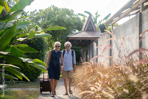 Senior Couple Walking With Suitcase In Resort Area photo