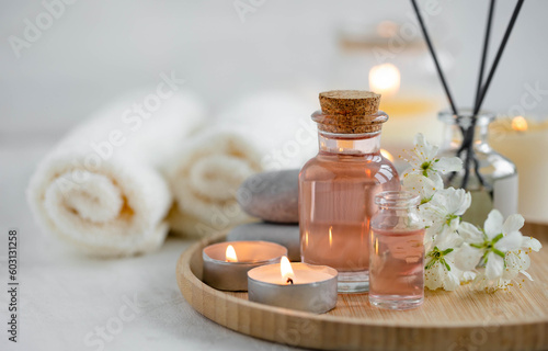 Aromatherapy, home decor concept. Glass perfume bottle, elegant composition with spring flowers. Burning candles, spa setting, essential oils, organic pure aromatic ingredients, atmosphere of relax