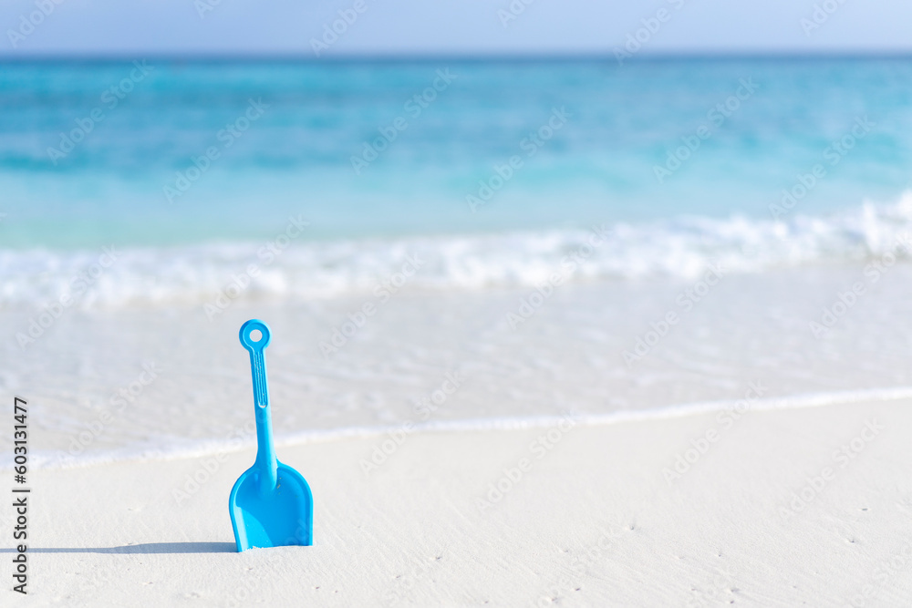 Children's toy shovel on the beach against the background of the ocean in the Maldives. Children's toy shovel on the beach against the background of the ocean in the Maldives.