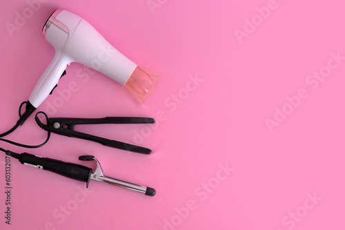 Fototapeta Naklejka Na Ścianę i Meble -  set para arrumar cabelo prancha, secador, boblis em fundo cor de rosa 