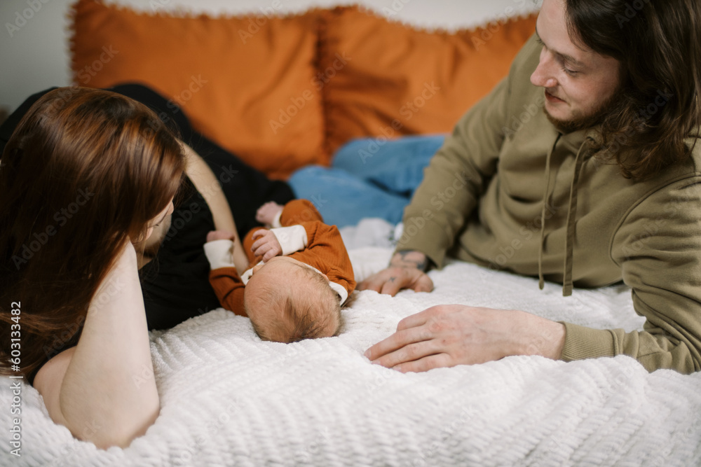 Smiling happy parents on bed at home with their newborn baby Smiling happy parents on bed at home with their newborn baby
