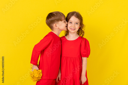 First love. A little boy gives flowers to a little girl and kisses her cheek.