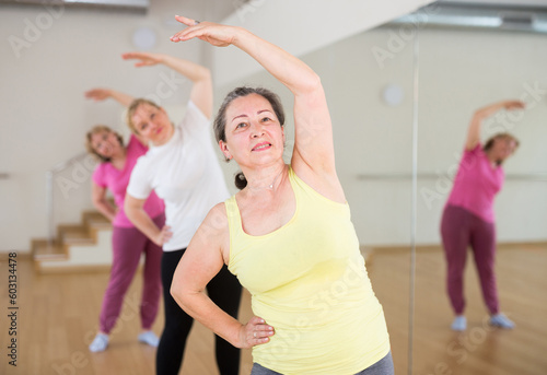 Portrait of active mature woman enjoying group training in dance studio