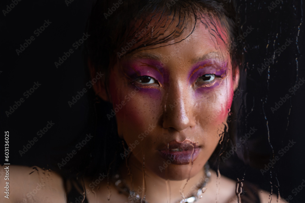 Asian woman with fashion pink makeup through wet glass Asian woman with fashion pink makeup through wet glass