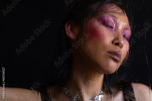 Asian woman with fashion pink makeup through wet glass  photo