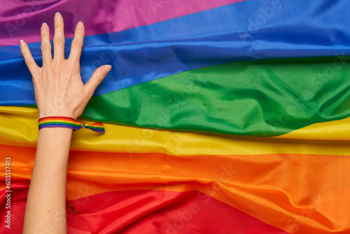 Hand with LGTB community bracelet on rainbow flag background