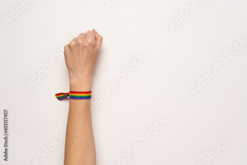 Fist fight of woman with LGBT rainbow bracelet on white background