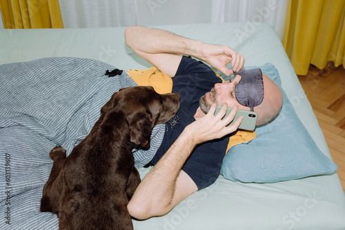 Man in the sleep mask is awake and having phone call.