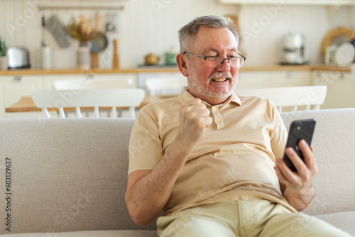 Obraz na płótnie Middle aged senior man euphoric winner with smartphone