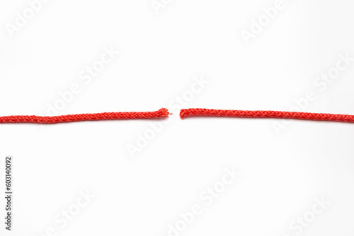 Red rope cut into two parts on a white isolated background. The concept of breaking human relationships or problems in business. Red broken line in the form of a thread