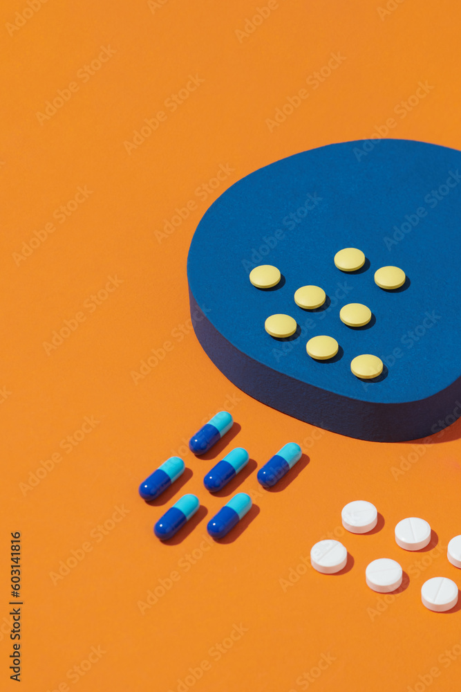 Creative layout with pills and bottle on two tone orange and blue Creative layout with pills and bottle on two tone orange and blue