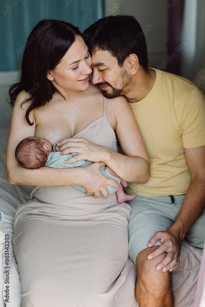 Happy parents breastfeeding baby in bedroom Happy parents breastfeeding baby in bedroom