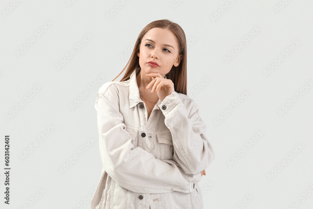 Pretty thoughtful young woman in stylish clothes on light background Pretty thoughtful young woman in stylish clothes on light background