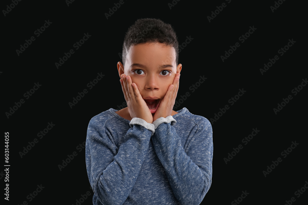 Scared little African-American boy on black background Scared little African-American boy on black background