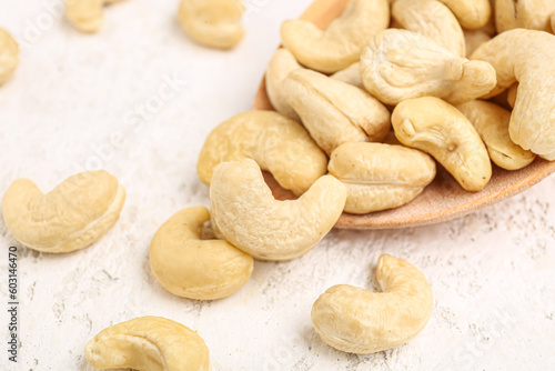 Spoon with tasty cashew nuts on light background