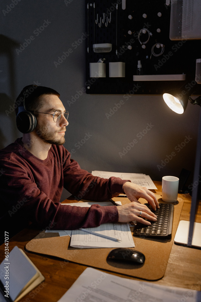A man uses a computer while working at night A man uses a computer while working at night