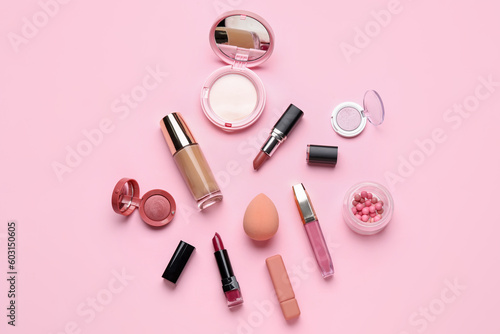 Decorative cosmetics with lipsticks and sponge on pink background