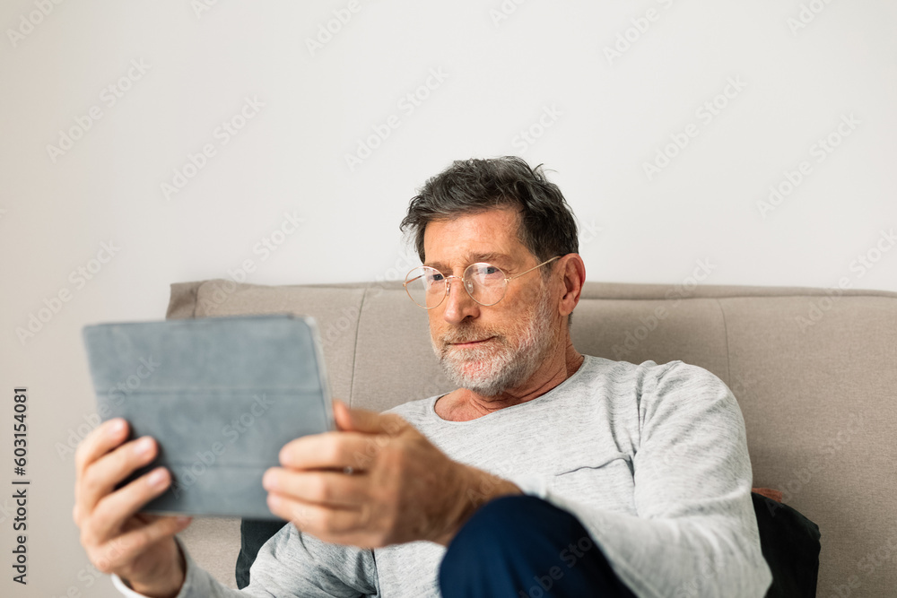 Senior Man Sitting on Couch and Using Tablet Senior Man Sitting on Couch and Using Tablet