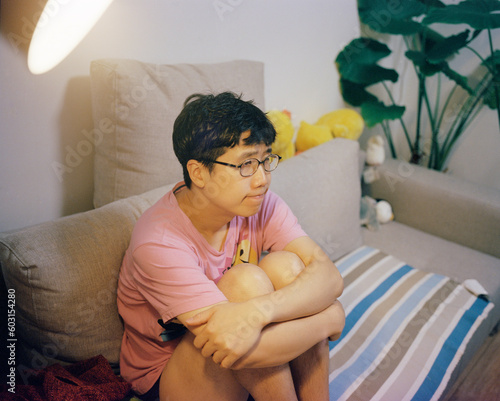 The man wearing glasses sat on the sofa feeling aggrieved