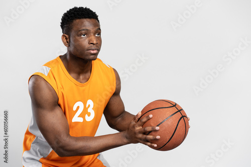 Serious, professional African basketball player holding ball isolated on white background © Maria Vitkovska
