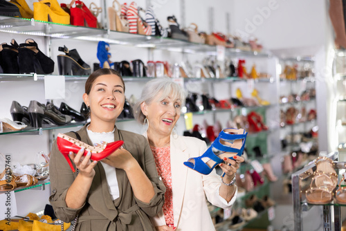 Two female customers choosing fashionable high heel shoes in a shoe store