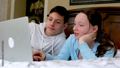 a boy and a girl on the bed near the computer having fun fooling around take their hands away from the keyboard pinch their fingers fight fight laugh have fun tickler spend time together look