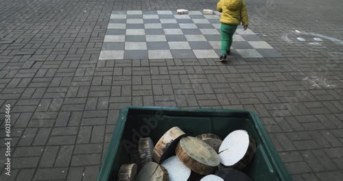 Blonde Toddler Swiftly Carries Oversized Chess Pieces for a Giant Checkers Game photo