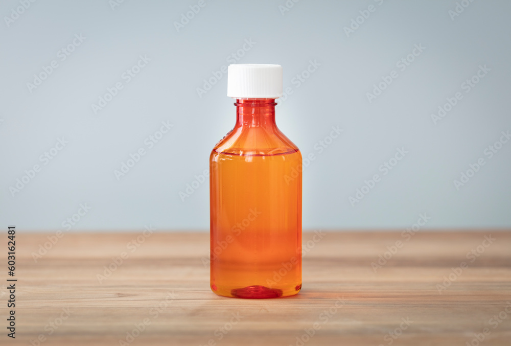 Bottle with liquid medicine. Transparent orange vial with lid on neutral background. Stop your cold today. Copy space for text or image. Bottle with liquid medicine. Transparent orange vial with lid on neutral background. Stop your cold today. Copy space for text or image.