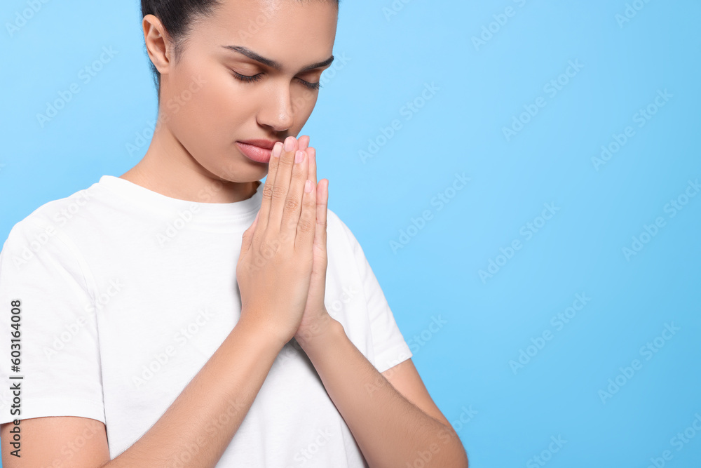 African American woman with clasped hands praying to God on light blue background. Space for text African American woman with clasped hands praying to God on light blue background. Space for text