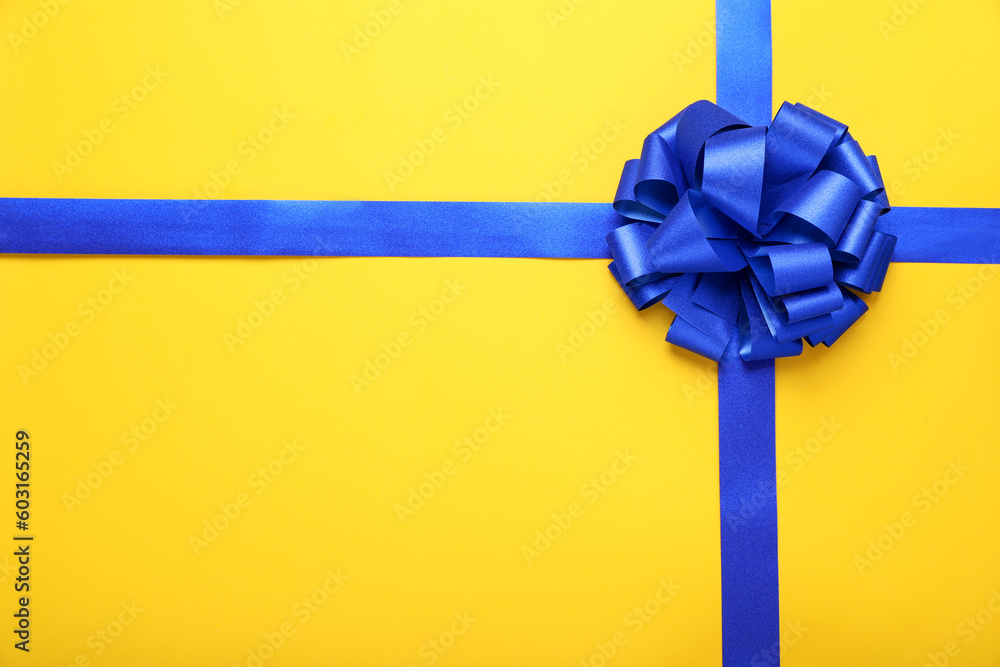 Blue ribbons with bow on yellow background, top view. Space for text Blue ribbons with bow on yellow background, top view. Space for text
