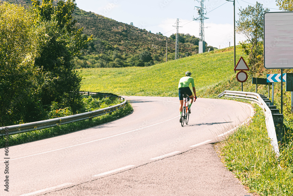 A cyclist with a cycling maillot doing a mountain route to reach the top with the Fito, Asturias, at the end in a sunny summer day 