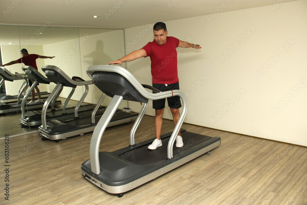 Fototapeta premium Forty-year-old dark-haired Latino adult man exercises his legs on the treadmill as a treatment for diseases such as tendonitis, tendon rupture or cruciate ligament injury