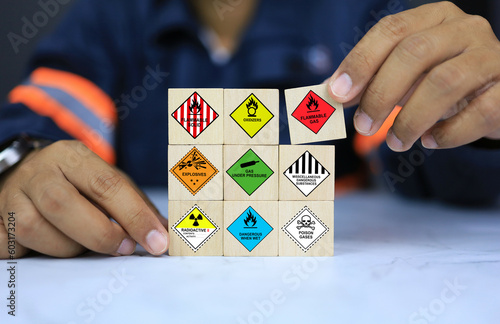 Security officers arrange dangerous warning sign icon on wooden cube for operator safety such as explosions, radioactive, toxic gases, etc. photo