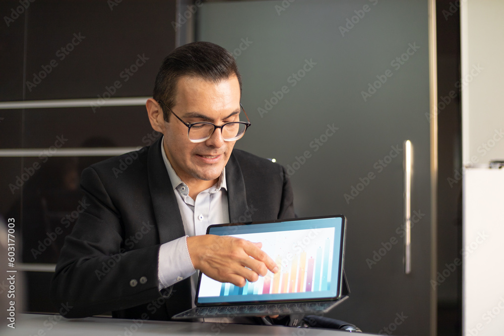 young boss CEO businessman pointing and showing graphics on his tablet in a conference, focused and speaking young boss CEO businessman pointing and showing graphics on his tablet in a conference, focused and speaking