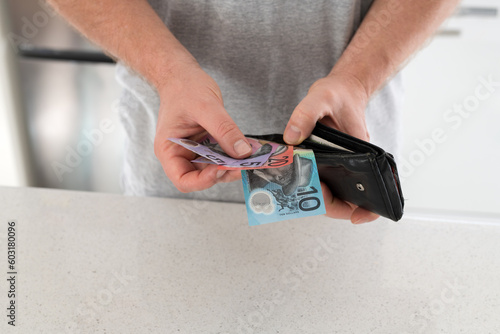 Male hands taking Australian bank notes from a worn black wallet - financial photo