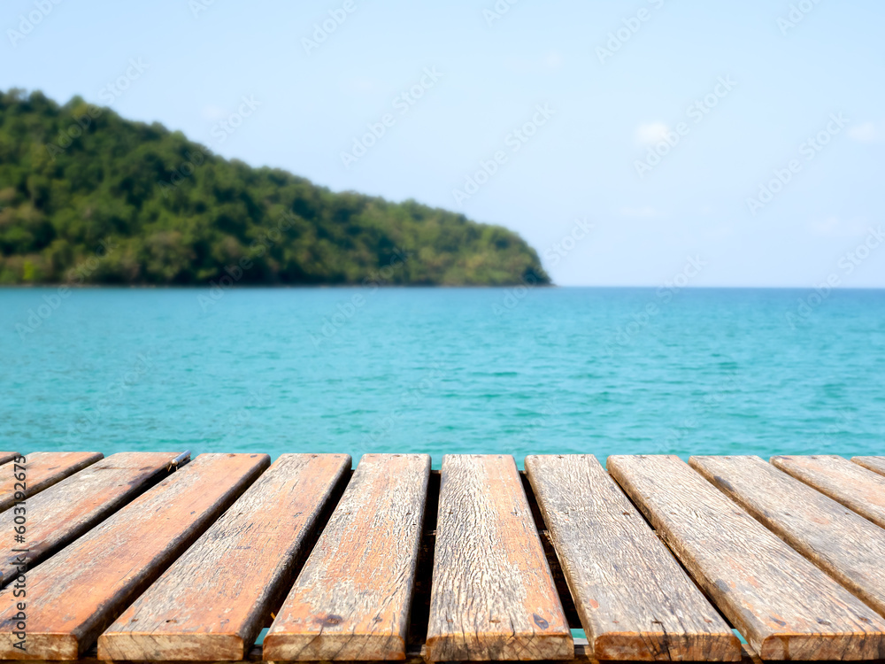 Empty old wooden desk template on tropical sea, island and summer sky background. Brown top table or grunge wood plank space for place products, packaging for summertimes advertising campaign.