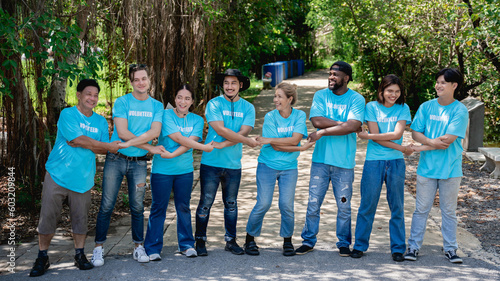 .Group of volunteers for charity join hands and arm around in the forest park area. Environmental protection project.